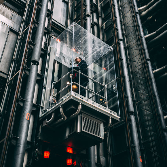 Businessman in glass elevator going up