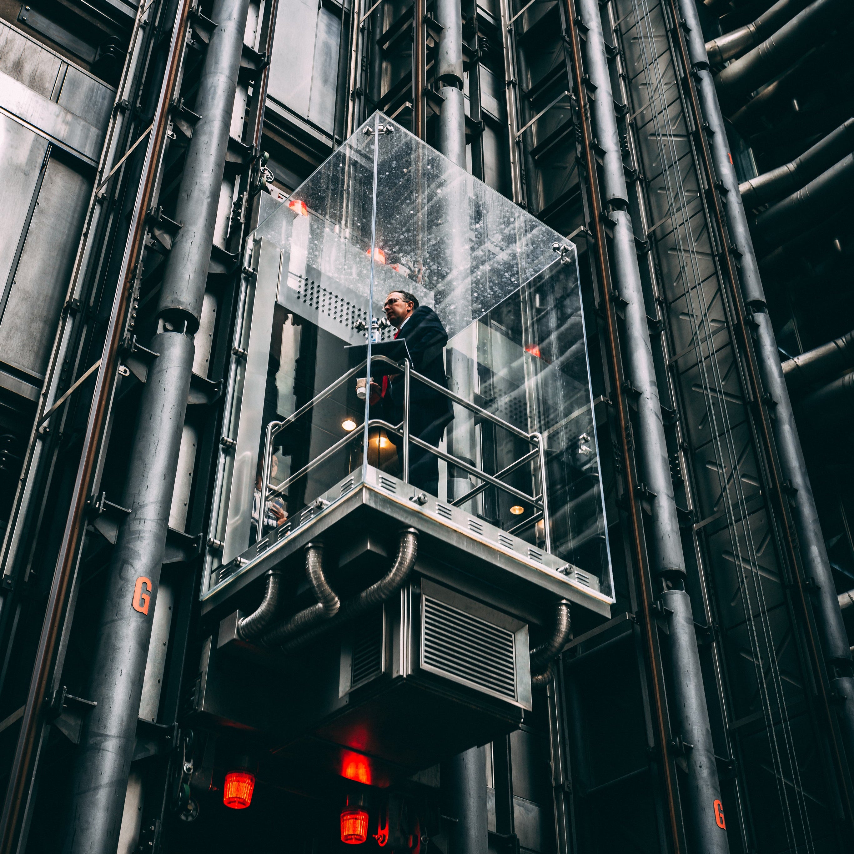 Businessman in glass elevator going up